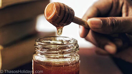 Hand taking some honey from a bowl